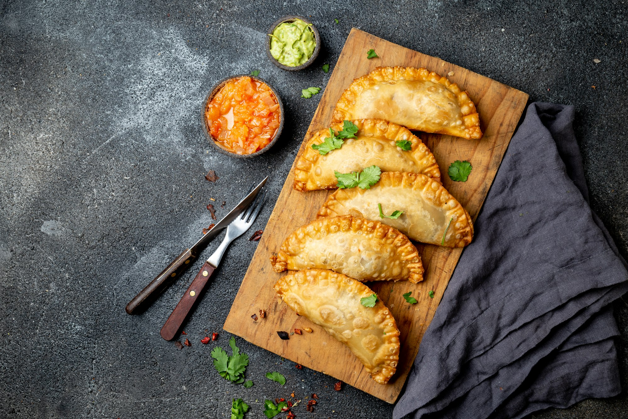 Latin American fried empanadas with tomato and avocado sauces. Top view