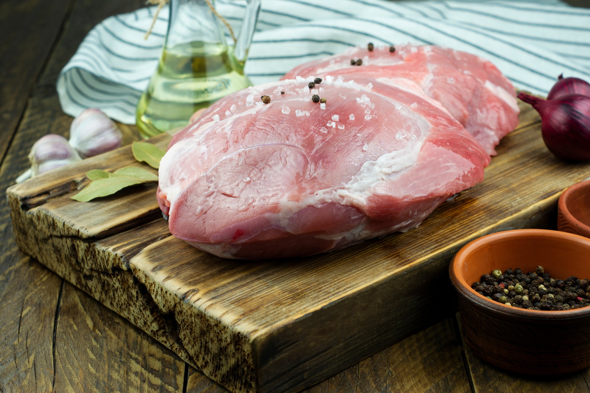 a large piece of raw steam tenderloin on a wooden board for cooking in the oven with spices.