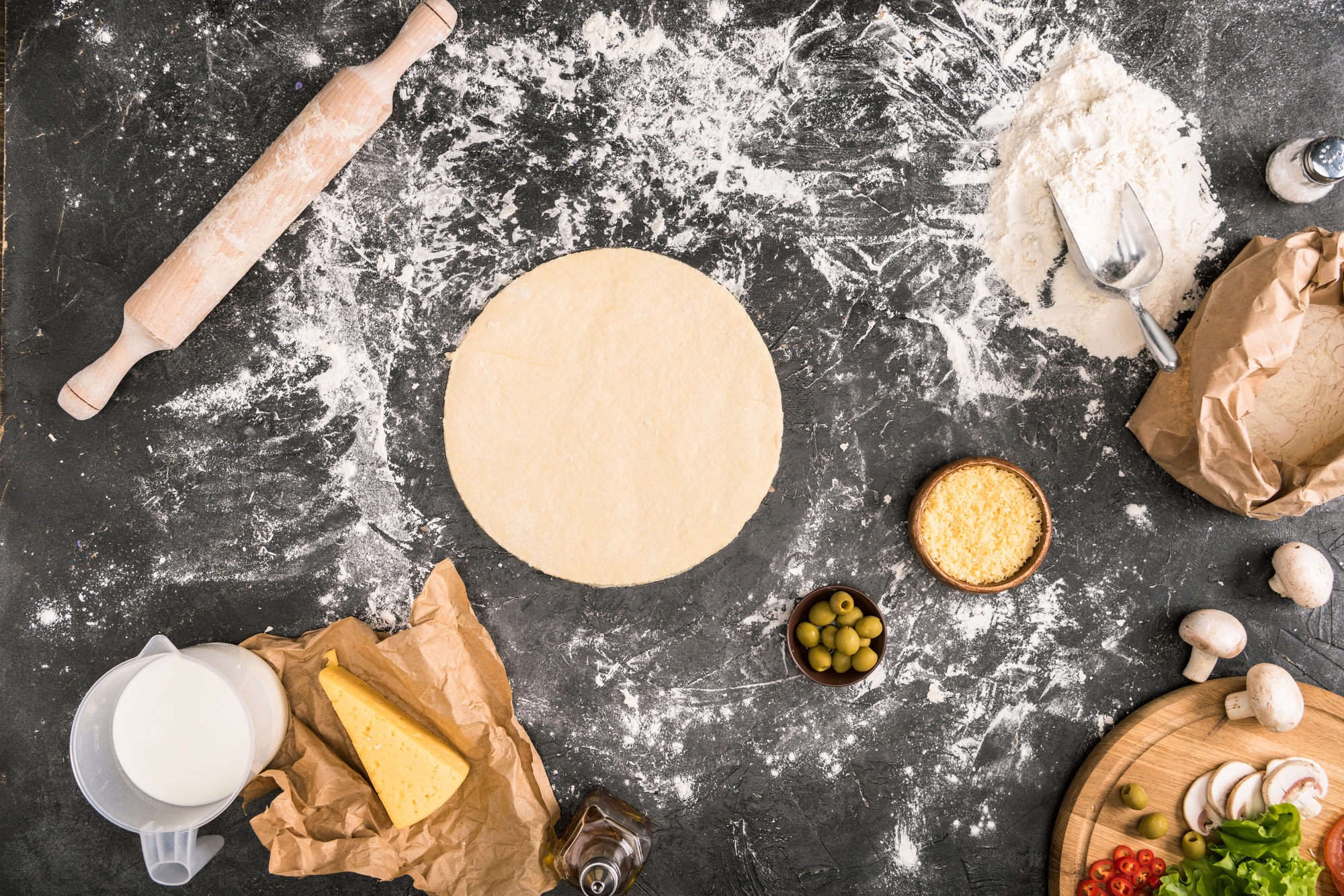 top view of pizza dough with ingredients on grey background